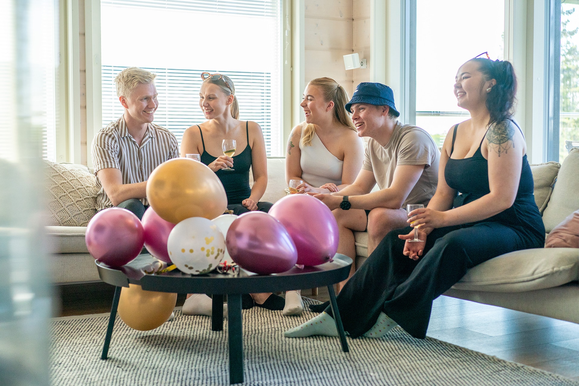 Joukko nuoria aikuisia viettävät syntymäpäiviä ja hymyilevät.